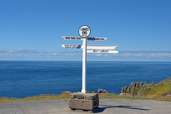 The sign at Lands End showing the distances to far off land marks, with the sea in the background and no other land in sight.